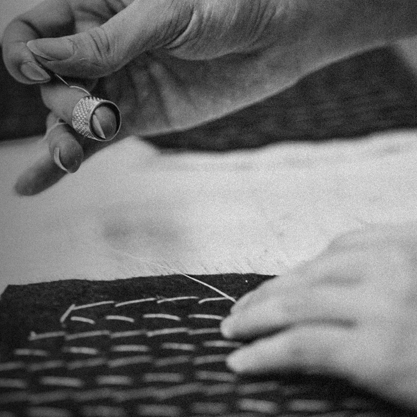 Detailed black and white view of hand-stitching fabric